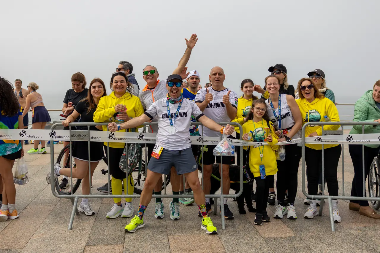 Grupo de participantes reúne-se junto à barreira da prova, a festejar.
