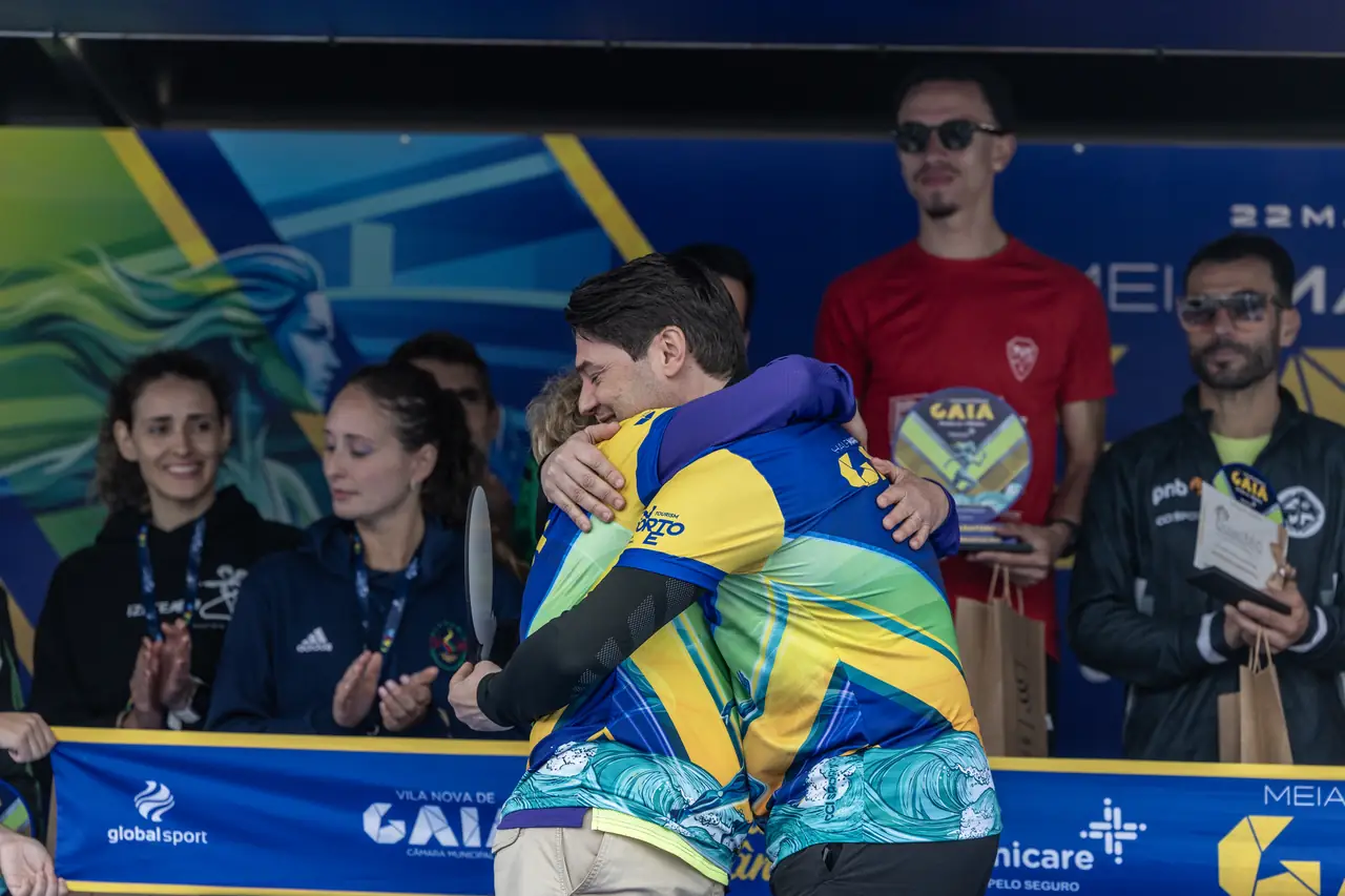 Dois corredores abraçam-se, emocionados, com as medalhas ao peito.