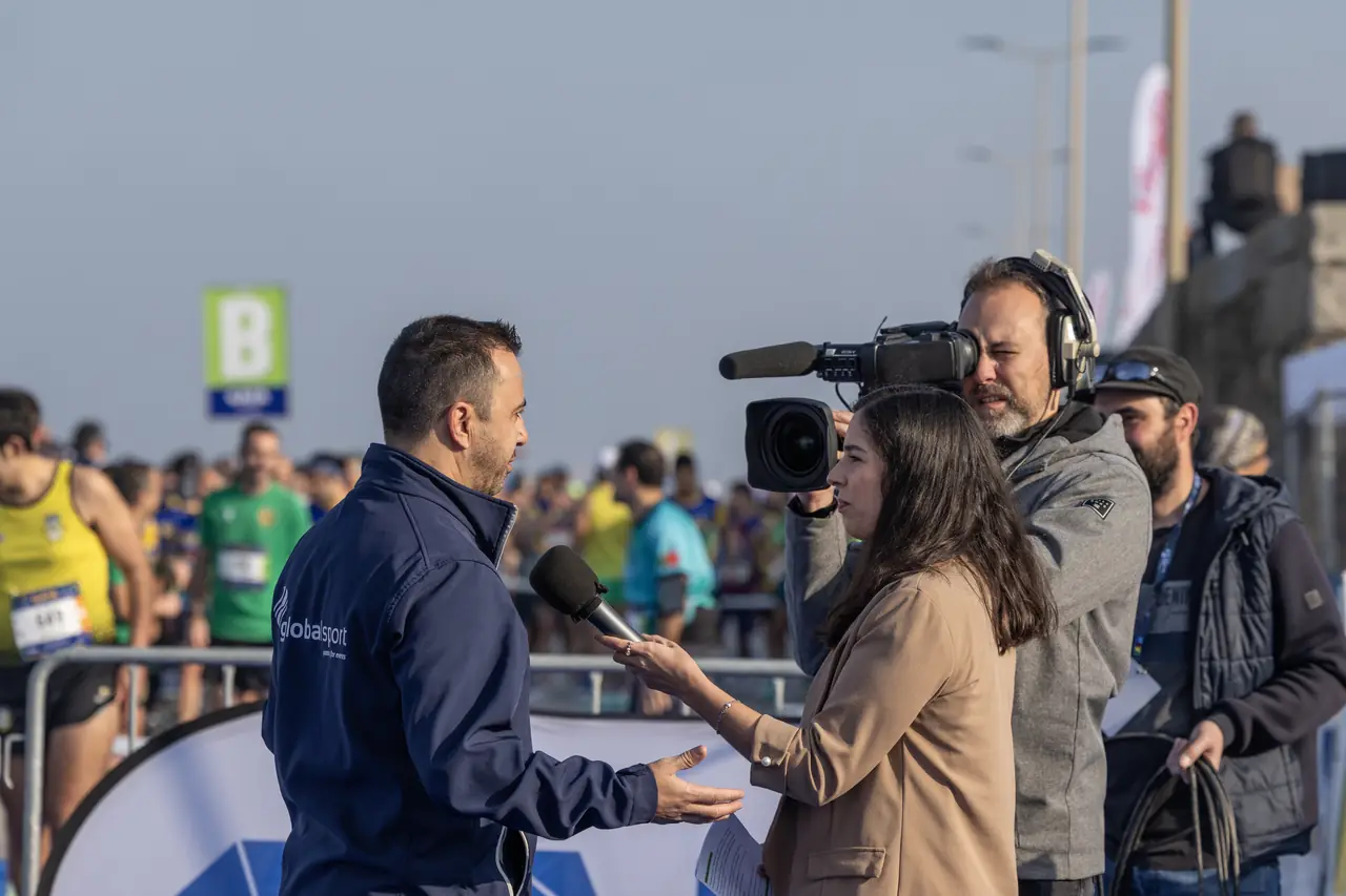 Jornalista entrevista um convidado junto ao pórtico da prova.