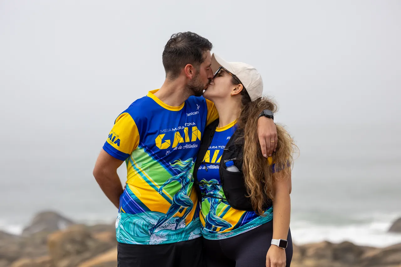Casal com as cores da Meia Maratona de Gaia abraça-se junto à costa atlântica, depois da prova.