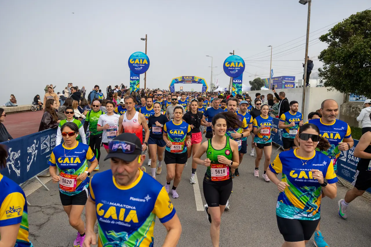 Corredores da Meia Maratona de Gaia 2026 em prova na marginal, vistos de frente, com centenas de participantes atrás.
