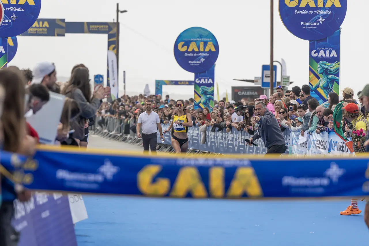 Centenas de corredores atrás da fita da partida da Meia Maratona de Gaia 2026, com o público encostado às barreiras dos dois lados.