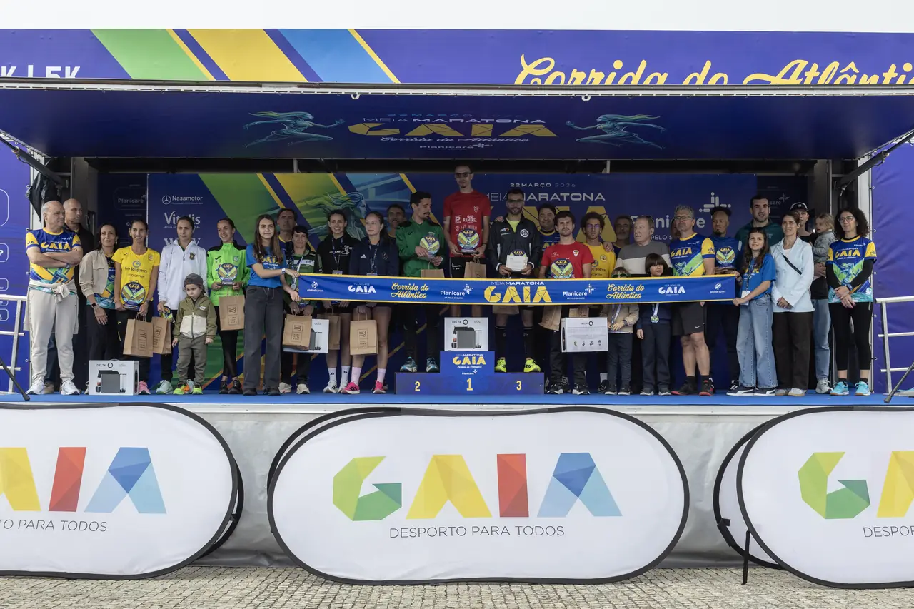 A cerimónia de prémios de 2026 no palco da meta: os primeiros classificados no pódio com os troféus, rodeados pela organização e pelas famílias.